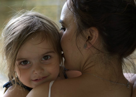 aboriginal mum cuddling and whispering to her toddler daughter