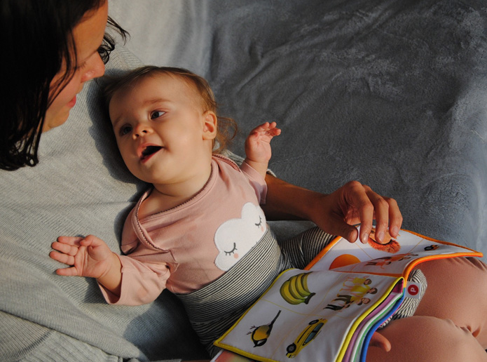 A mum cuddles with and reads to her baby